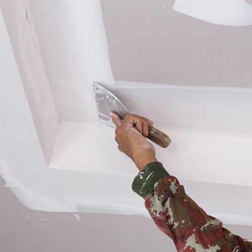 hand of worker using gypsum plaster ceiling joints at construction site hand of worker using gypsum plaster ceiling joints at construction site